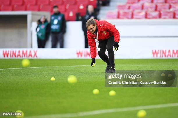 Security are seen collecting tennis balls from the pitch which we're thrown in protest against the German Football League during the Bundesliga match...