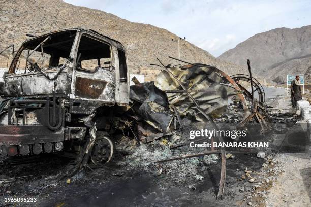 Man walks past a charred truck container torched by armed separatist group Balochistan Liberation Army at central Bolan district in Balochistan...