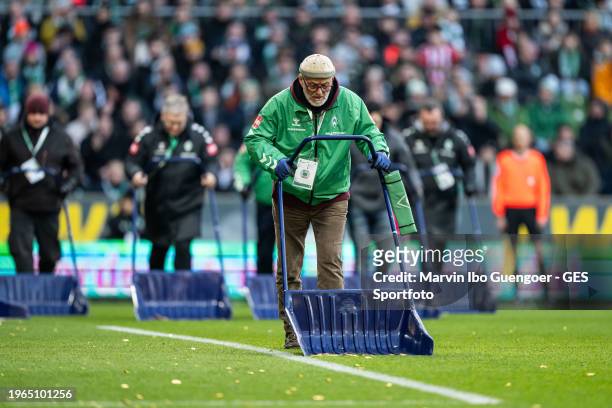 Members of the security staff collect chocolate gold coins that fans had thrown onto the pitch in protest against investors during the Bundesliga...