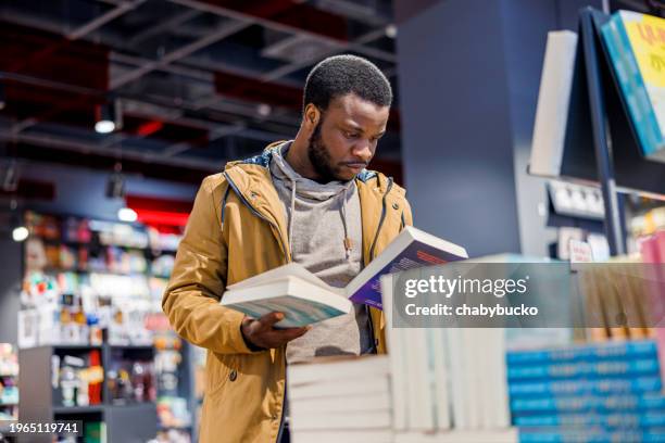 african american man chooses books in bookstore - book shop stock pictures, royalty-free photos & images