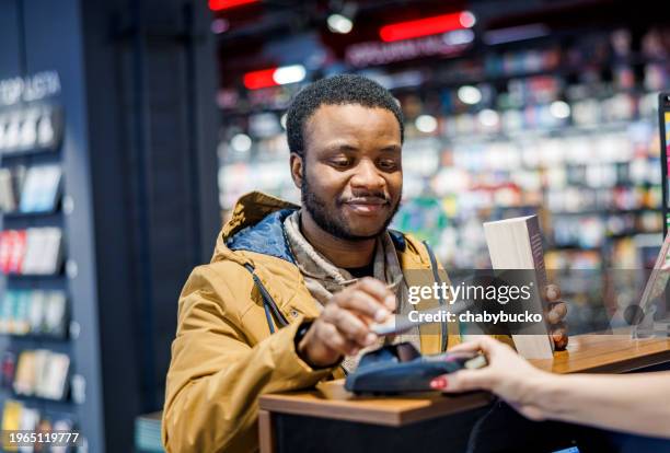 homme achetant un livre dans une librairie - librairie photos et images de collection
