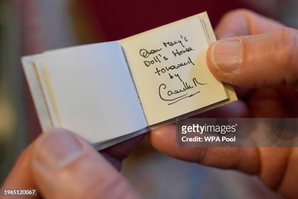 Glenn Bartley, head of the Royal Bindery, shows a miniature book, written by Queen Camilla, during a reception at Windsor Castle for authors,...
