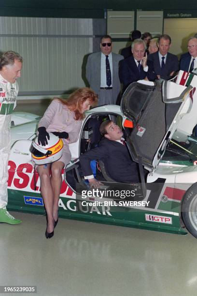 The Duchess of York watches as her husband Prince Andrew attempts to climb from the cockpit of a Jaguar XJR-10 race car during a tour of Jaguar's new...