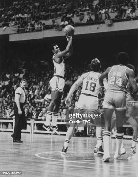 American basketball player Jo Jo White, Celtics point guard, jumps as he takes his shot, watched by his teammate, American basketball player Dave...