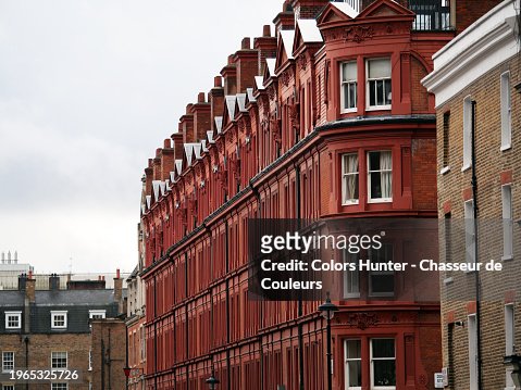 View of old brown and red brick residential buildings in the Kensington district of London, England, United Kingdom. Cloudy sky. 
Natural light and colors.
No people.