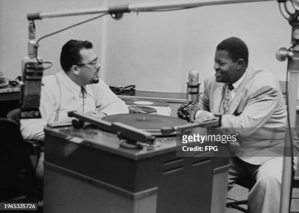 American disc jockey Al 'Jazzbo' Collins in conversation with Canadian jazz pianist and composer Oscar Peterson during a broadcast on Oscar Peterson...