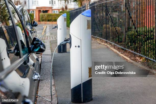 electric cars charging at a street charger point. london, uk - stromtankstelle stock-fotos und bilder