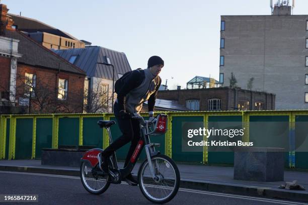 Bike rider commutes on a Santander bike in Hackney in early morning winter sun on the 26th of January 2024, London, United Kingdom. Santander bikes...