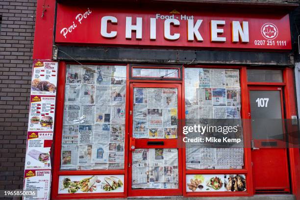 Closed down chicken shop business with newspaper covering the windows on 15th January 2024 in London, United Kingdom. Things have been difficult for...