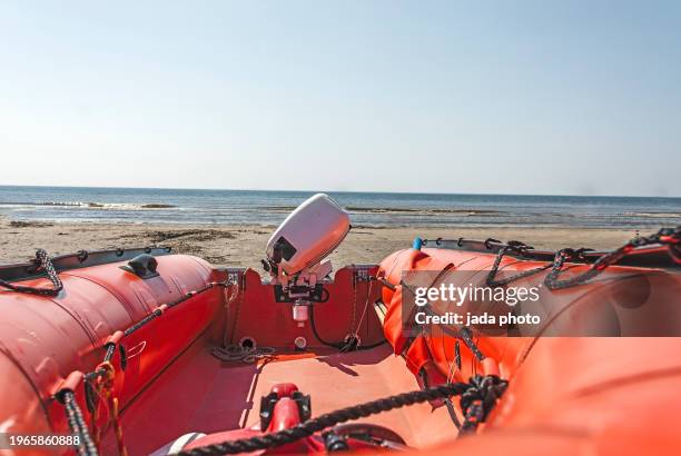 perspective of an orange rubber lifeboat with outdoor motor - bote neumático fotografías e imágenes de stock
