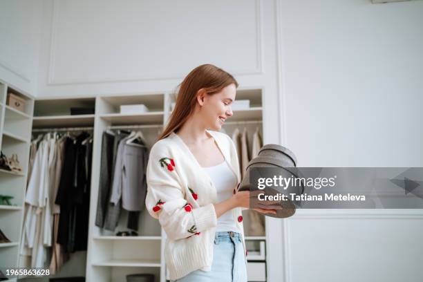in a dressing room, smiling long-haired woman stands with clothing and accessories boxes - woman clothes donation stock pictures, royalty-free photos & images