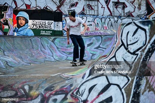 Skateboarder practises next to a graffiti made by street artist Itaewon, depicting Palestinian citizen journalist, Doaa Mohamed, in east London, on...