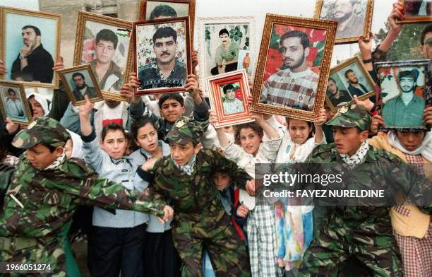 Palestinian children, holding portraits of their incarcerated fathers and brothers, march through the streets of Gaza, 30 January, to demand their...