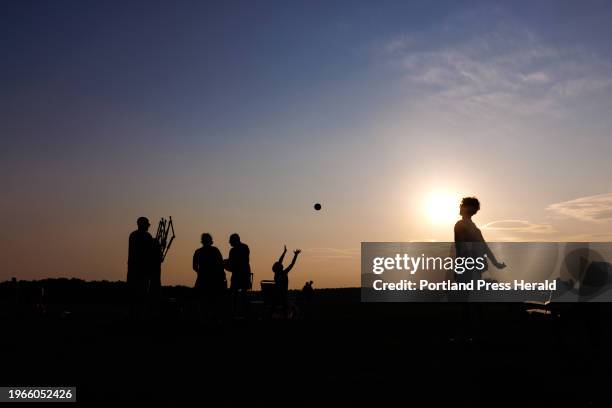 Beachgoers silhouetted in the setting sun at Kettle Cove on Friday, July 28, 2023.