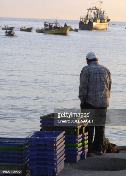 Palestinian man stands next to fish plastic containers at Gaza City's port 25 April 2001. The Israeli navy temporarily closed off Gaza's southern...