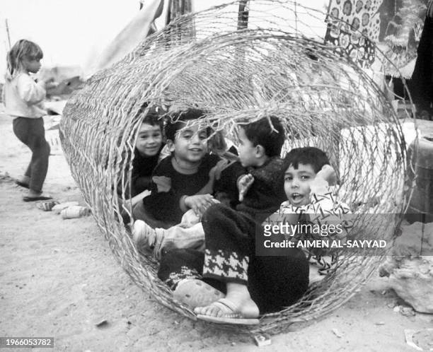 Palestinian children play 10 December inside a coil of chicken wire in a desert camp near the Libya-Egyptian border. They are among the 250...
