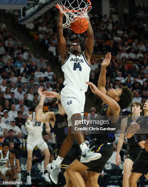 Josh Uduje of the Utah State Aggies slam dunks the ball over Christian Wise and Tibet Gorener of the San Jose State Spartans during the second half...