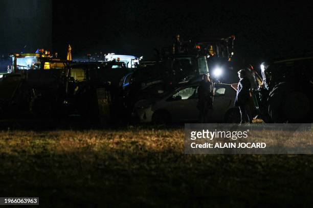 Journalist is silhouetted while delivering a televised report next to tractors belonging to French farmers of the CR47 union during an overnight...