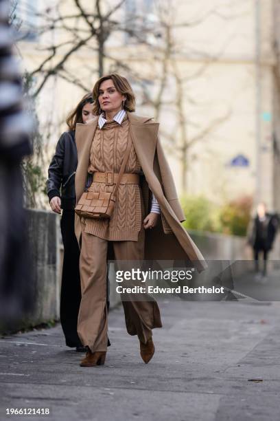 Guest wears earrings, a triped shirt, a brown knitted wool pullover, a leather belt, a Bottega Veneta woven leather bag, flared pants, a beige /...