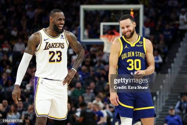 LeBron James of the Los Angeles Lakers and Stephen Curry of the Golden State Warriors make each other laugh during a stop in play in the first half...