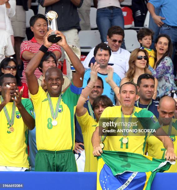 Flanked by teammates, Brazil's beach soccer team captain Junior Negao holds the trophy after winning the final of the FIFA Beach Soccer World Cup...