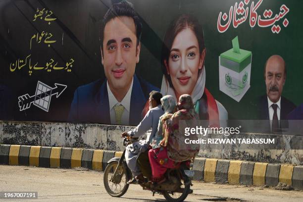 Commuters ride past an election campaign poster of the Pakistan Peoples Party in Karachi on January 31 ahead of Pakistan's upcoming general elections.