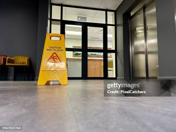 achtung: nassbodenschild an glastüren zum gebäudeeingang - glatteis stock-fotos und bilder