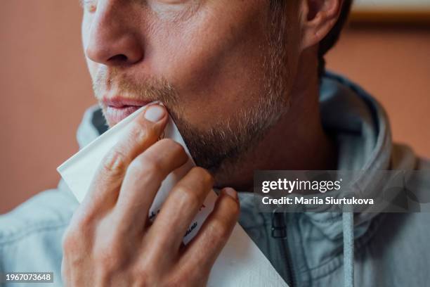 close-up of a man carefully wiping his mouth with a white paper napkin. - wipe mouth stock pictures, royalty-free photos & images