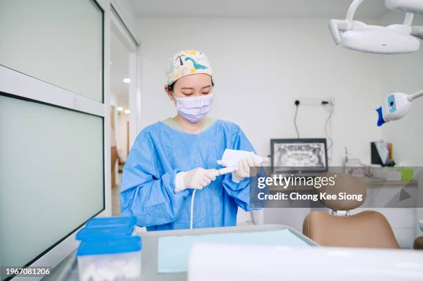 dentista asiática china haciendo limpieza para el próximo paciente. - consultorio dental fotografías e imágenes de stock