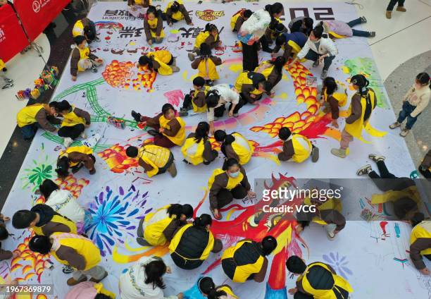 Children draw dragon-themed pictures on a canvas at a shopping center ahead of the Year of the Dragon on January 27, 2024 in Xuzhou, Jiangsu Province...
