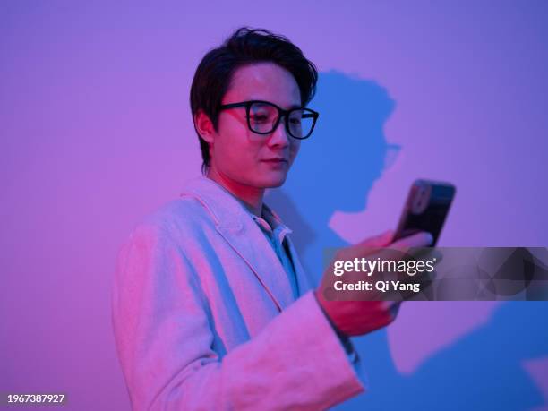 confident asian businessman holding smartphone in neon light - pride gradient stock pictures, royalty-free photos & images