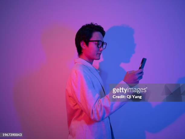 confident asian businessman holding smartphone in neon light - pride gradient stock pictures, royalty-free photos & images