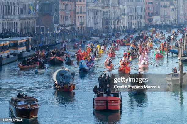 Boats carrying people dressed in masks, including a boat with the mouse "Pantegana" transit the Grand Canal near the Rialto Bridge during the...