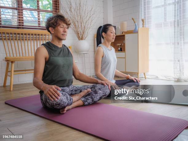 asian mature couple doing yoga or strength training exercises together at home - man meditating stock pictures, royalty-free photos & images