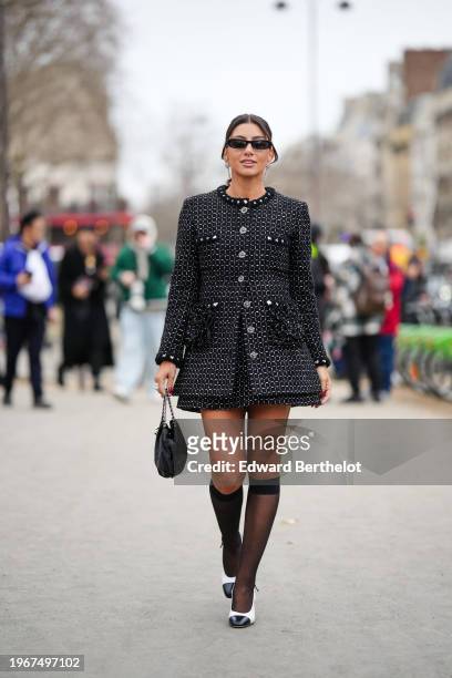 Guest wears jewelry and floral shaped earrings, sunglasses, make-up lipstick , a black and white tweed jacket, a bag, knee high tights, black and...