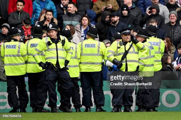 Member of the local police speaks on the phone as officers attempt to stop a pitch invasion during the Emirates FA Cup Fourth Round match between...