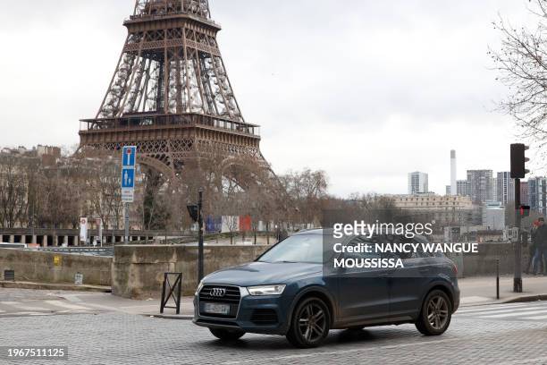 Local resident drives his sport utility vehicle in the center of Paris, with the Eiffel Tower seen in the background, on January 30, 2024. On...