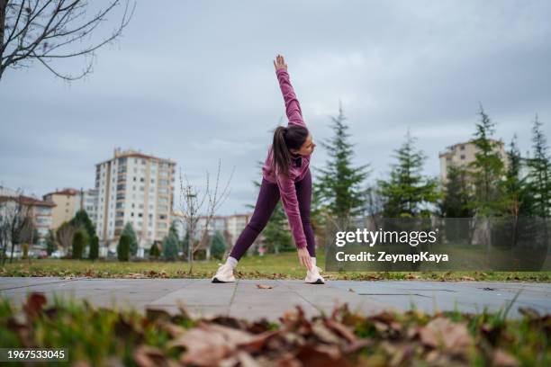 junge frau streckt sich beim training im öffentlichen park, nachts im freien. - zehenspitzen berühren stock-fotos und bilder