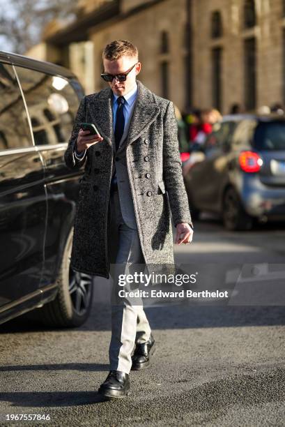 Guest wears sunglasses, a blue shirt, a tie, a gray coat, gray pants, black leather shoes , outside Dior, during the Haute Couture Spring/Summer 2024...