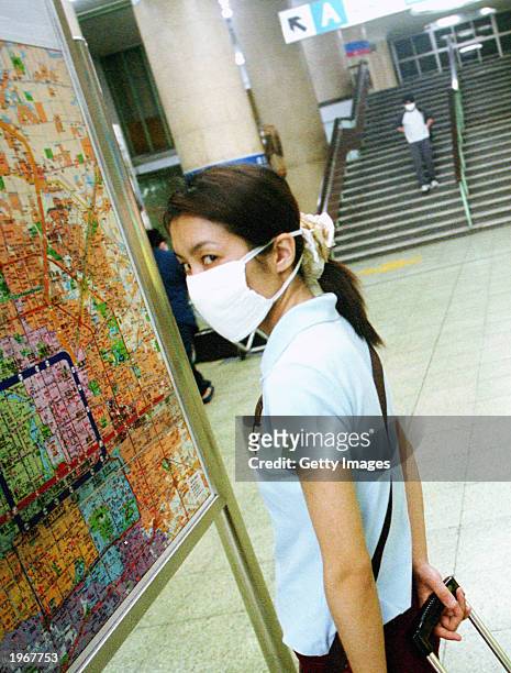 A woman wearing a protective mask in the Jianguomenwai subway station in Beijing, on May 2, 2003. At least 82 people have died in Beijing and more...