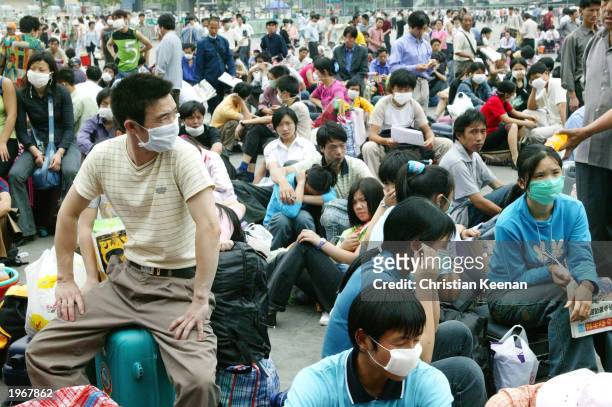 Migrant workers wait outside the train station before returning home because of the worry over SARS May 2, 2003 in Guangzhou, the capital of...