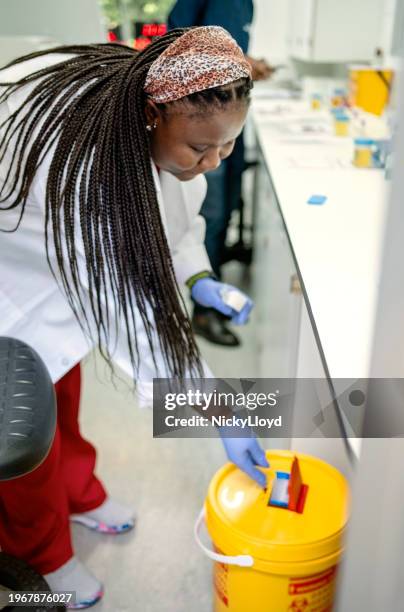 pathologin entsorgt den abfall in einem gelben klinischen abfallbehälter im labor - biogefährliche substanz stock-fotos und bilder