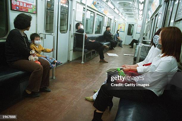 Travelers wearing protective masks sit in an almost deserted subway train in Beijing,on May 2, 2003. As a result of the Severe Acute Respiratory...