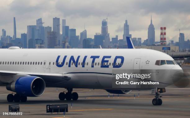 United Airlines airplane proceeds to a gate at Newark Liberty International Airport in front of the skyline of midtown Manhattan and the Empire State...
