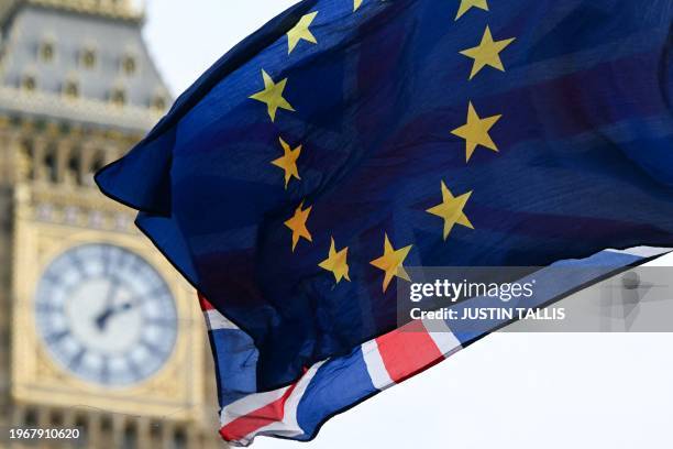Photograph taken on January 31, 2024 shows a European Union flag and a Union Jack flag flapping in the air in front of the Elizabeth Tower, commonly...