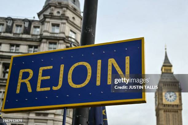 Photograph taken on January 31, 2024 shows a Placard reading "rejoin" in front of the Elizabeth Tower, commonly known by the name of the clock's bell...