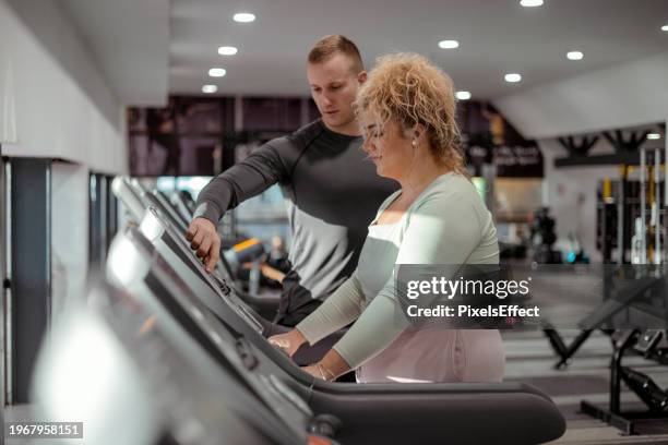 personal trainer and obese young woman running at the treadmill - sport determination stock pictures, royalty-free photos & images