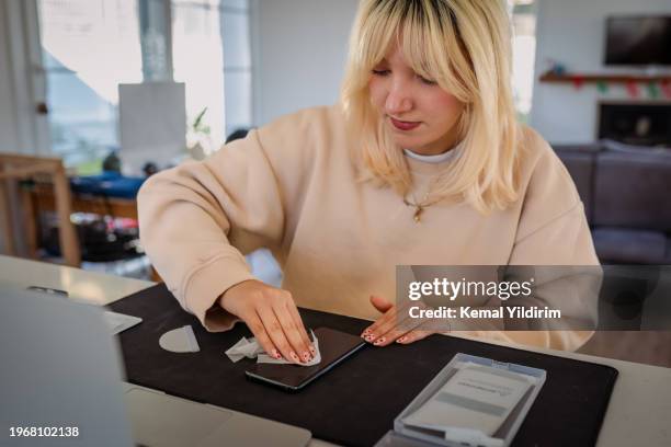 millennial girl changing mobile phone screen protector - lifehack stock pictures, royalty-free photos & images