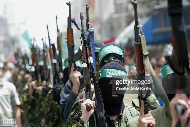 Masked Palestinian militant members of Hamas hold their weapons as they march during the funeral of their leader Youssef Abu Heen and his two...
