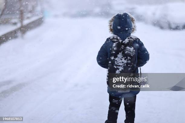 happy kid boy with having fun with snow on way to school - snowing stock pictures, royalty-free photos & images